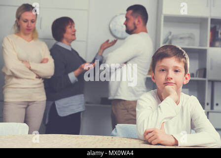 Sad desperate little boy during parents quarrel in home interior Stock Photo