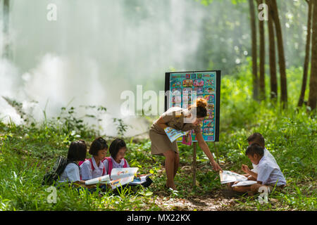 Sakonnakhon, Thailand - July 30, 2016: Beautiful teacher in uniform teaching her students outdoor class in forest public park in Sakonnakhon, Thailand Stock Photo