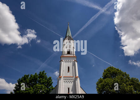 St.-Georg church in Gerzen, Bavaria, Germany with blue sky, clouds and contrails in the background Stock Photo