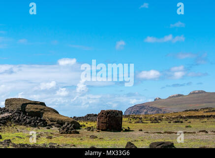 Ahu Te Pito Kura with fallen Moai and view of Pike extinct volcano, Easter Island, Rapa Nui, Chile, with blue sky Stock Photo