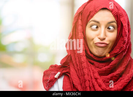 Young arab woman wearing hijab making funny face fooling Stock Photo