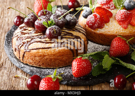 Dessert cakes with chocolate, mint, strawberries, cherries and blueberries close-up on the table. horizontal