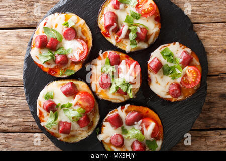 Appetizing of baked eggplant with cheese, tomatoes, sausages and herb close-up on the table. horizontal top view from above Stock Photo