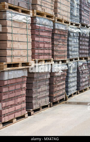 pallets with bricks in the building store. Racks with brick. Masonry, stonework. Several pallets with concrete brick stacked on top of each other in d Stock Photo