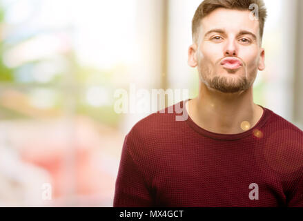 Handsome young man expressing love, blows kiss at camera, flirting Stock Photo