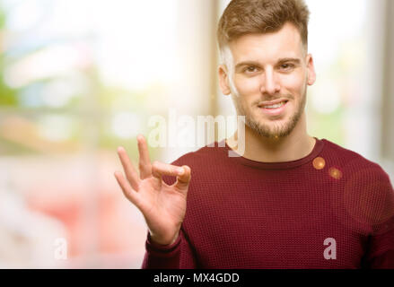 Handsome young man doing ok sign with hand, approve gesture Stock Photo