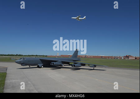 Boeing B-52H, 60-0005, poses in front of Oklahoma City Air Logistics Complex Bldg. 3001 following major overhaul while a Boeing E-6B TACAMO aircraft flies overhead on May 1, 2017, Tinker Air Force Base, Oklahoma. OC-ALC is responsible for depot level maintenance of both aircraft fleets with a large portion of the work taking place in the building shown behind. Stock Photo