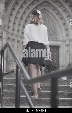 young female going back barefoot the stone stairs in historical center Stock Photo