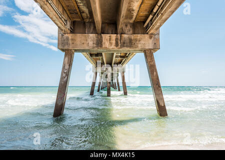 Under Okaloosa fishing pier in Fort Walton Beach, Florida during day with pillars, green shallow waves in Panhandle, Gulf of Mexico during sunny day Stock Photo