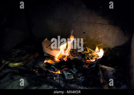 Burning paper, letters in indoor home interior fireplace with old retro vintage golden gold instruments tools, shovel, ash Stock Photo