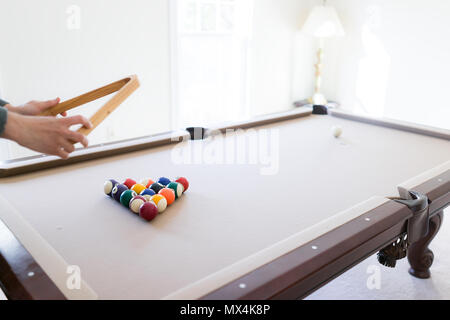 Interior house home with billiard pool table in living room, man moving lifting triangle rack, setting up game Stock Photo