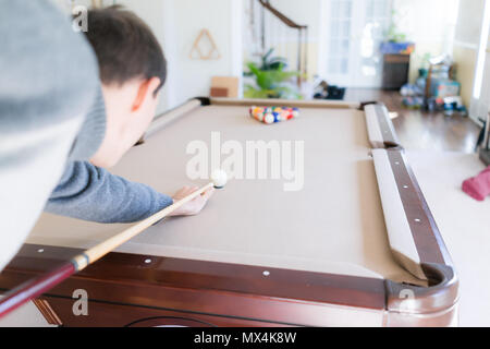 Interior inside house home with billiard pool table in living room, young man in winter cold sweater shooting white ball during game start with cue Stock Photo