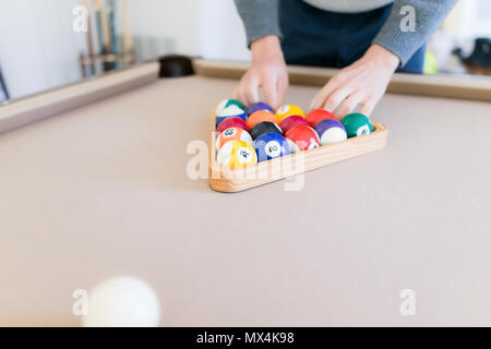 Interior inside house home with billiard pool table in living room, closeup of wooden triangle rack with 15 balls, setting up eight ball game Stock Photo