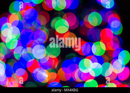 Christmas bokeh abstract background with red, blue and green, orange circles illuminated decoration lights on tree at night evening dark black Stock Photo