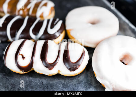 Chocolate brown and white icing long john donuts closeup on bakery tray, deep fried vanilla, delicious tasty Stock Photo