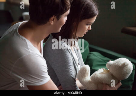 Boyfriend apologizing offended girlfriend presenting teddy bear  Stock Photo