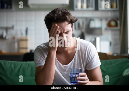 Young man suffering from headache, migraine or hangover at home Stock Photo