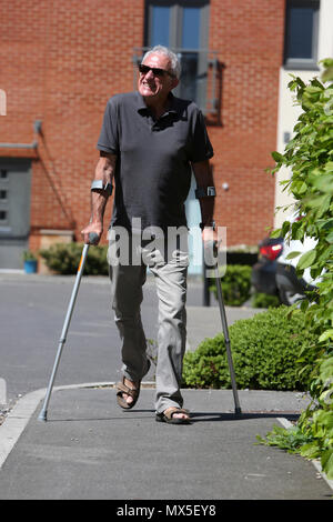 An older man pictured walking with crutches on a bad leg in Chichester, West Sussex, UK. Stock Photo