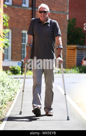 An older man pictured walking with crutches on a bad leg in Chichester, West Sussex, UK. Stock Photo