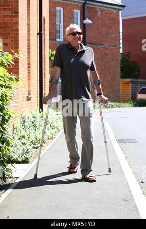 An older man pictured walking with crutches on a bad leg in Chichester, West Sussex, UK. Stock Photo