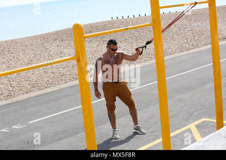 A man pictured using outdoor exercise equipment on the beach in Bognor Regis, West Sussex, UK. Stock Photo