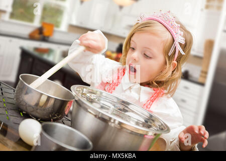 Cute Baby Girl Playing Cook With Pots and Pans In Kitchen. Stock Photo