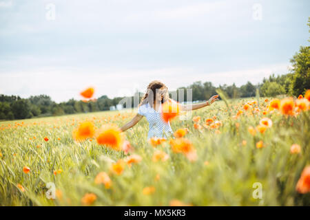 young curly carefree woman running through a field of wildflowers on a summer day Stock Photo