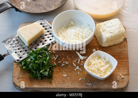 Frittata ingredients: Whisked eggs & milk, halloumi and parmesan cheese, cut basil Stock Photo