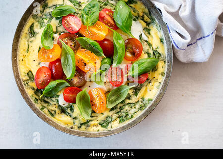 Basil frittata with halloumi, mixed tomatoes and basil leaves Stock Photo