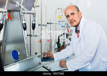 Attentive mature man working on quality of products in winery lab Stock Photo