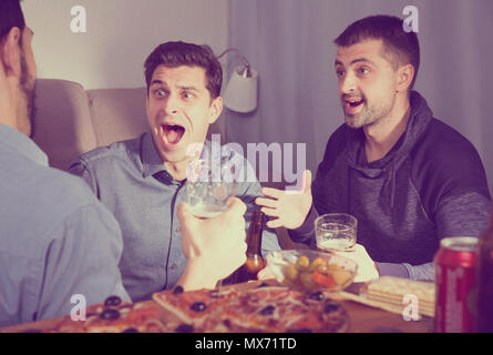 Friendly meeting in men company over beer with pizza at home Stock Photo