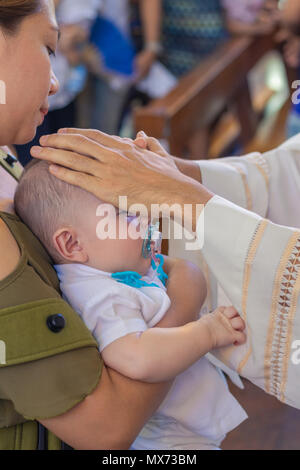 Catholic priest blessing a new born baby boy during a baptism. Stock Photo