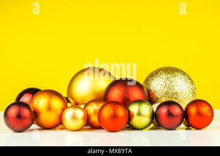 many multicolored christmas balls on yellow background Stock Photo