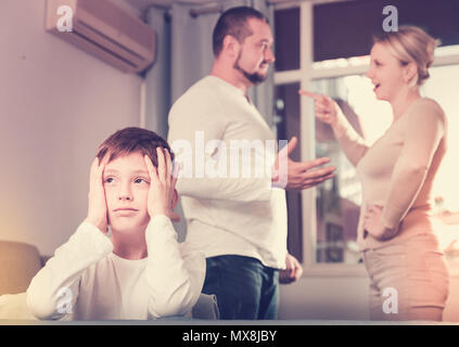 Sad desperate little boy during parents quarrel in home interior Stock Photo