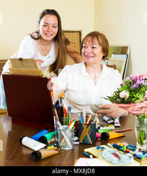 Cheerful experienced senior teacher gives advice to the beginner. Focus on the mature woman Stock Photo