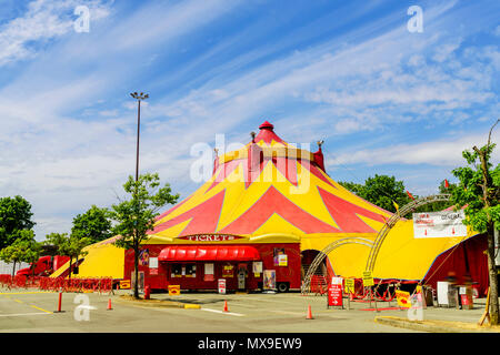 Domes of a caravan circus in the city, green trees, cars in a parking lot, a blue sky with dense clouds on a summer day Stock Photo