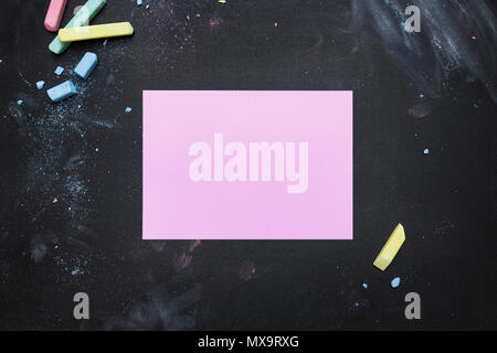 Blackboard tabletop scene with colored chalk and a blank pink paper Stock Photo