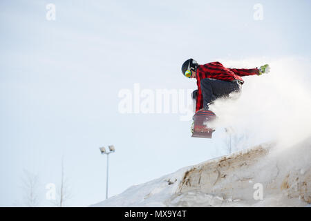 Photo of man with snowboard jumping from snowy mountain slope in afternoon Stock Photo