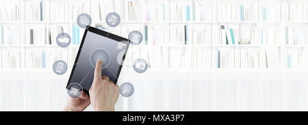 hand touching digital tablet with icons isolated on library background Stock Photo
