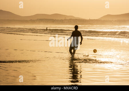 Silhouette of a single man playing football (soccer) at ...