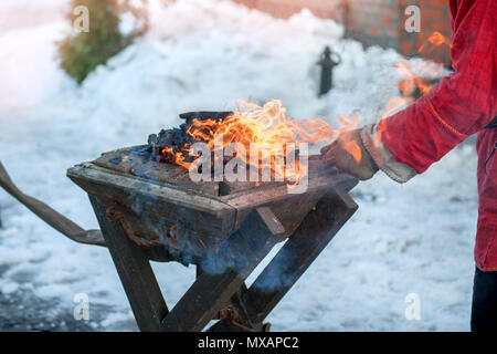 The hands of a blacksmith forging metal parts on the old anvil over an open fire. Folk craft Stock Photo