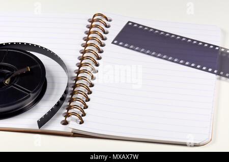 Group of objects. Notebook, film strip and rolled film on white background. Stock Photo