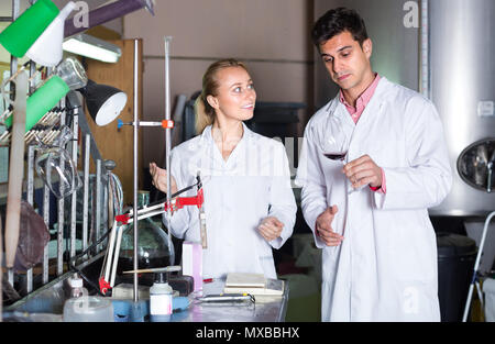 Two laboratory technicians in white uniform working at wine factory Stock Photo