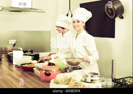 Friendly smiling female chefs preparing food on restaurant kitchen Stock Photo