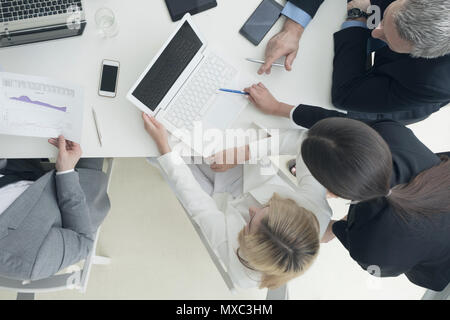 Business people brainstorming at office desk, analyzing financial reports and working with laptops and tablets Stock Photo