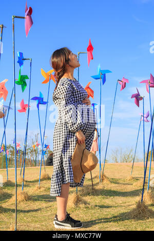 Asian pregnant woman in the middle of colorful pinwheel field Stock Photo