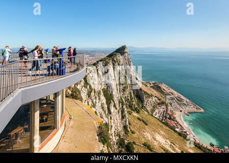 Gibraltar, UK - May 18, 2017: Tourists and Barbary Apes on the viewing platform with The Rock and the Spanish coastline to the rear, Gibraltar, United Stock Photo