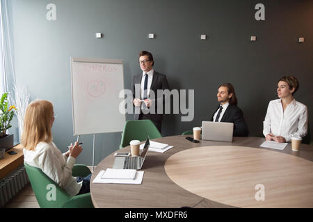 Serious male coach giving presentation on flipchart to business  Stock Photo