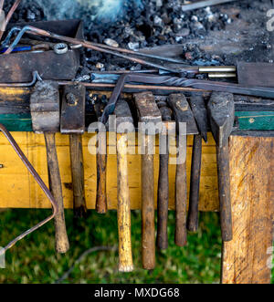 Some forging hammers hang in front of the forge fire ready to hand Stock Photo