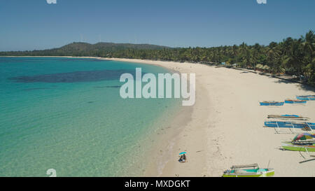 Aerial view of beautiful tropical beach Saud with turquoise water in blue lagoon, Pagudpud, Philippines. Ocean coastline with sandy beach and palm trees. Tropical landscape in Asia. Stock Photo